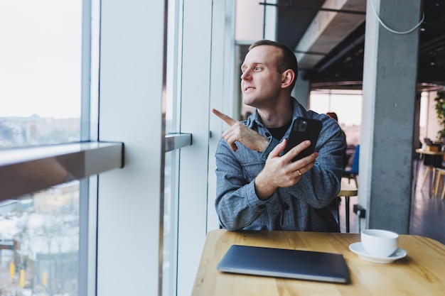 Gerente masculino confiado sentado en un espacio de trabajo moderno en una computadora portátil y hablando por teléfono trabajo remoto