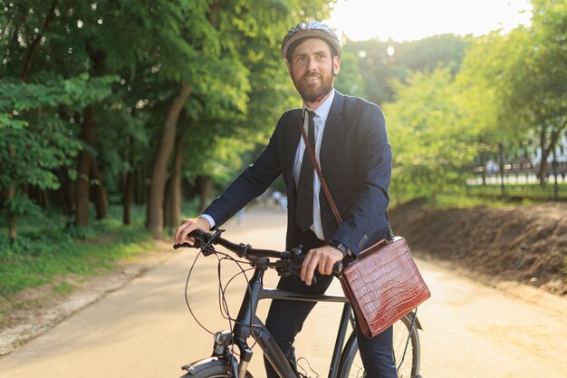 Foto gerente masculino de terno andando de bicicleta enquanto chega ao local de trabalho