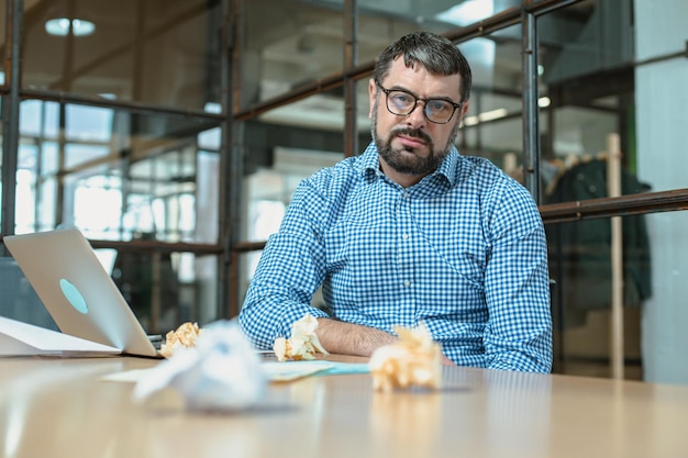 El gerente masculino se ve cansado a través de los espectáculos mientras trabaja duro en la oficina