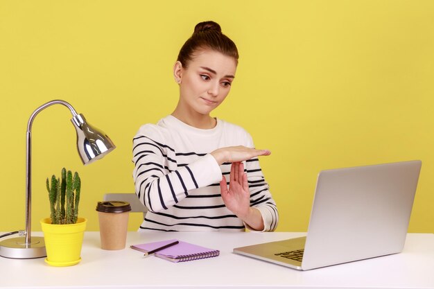 Gerente de mujer cansada que muestra el gesto de tiempo de espera mirando la pantalla del portátil hablando por videollamada