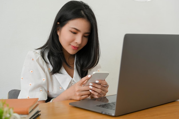 Gerente mujer sentada en su escritorio de oficina y charlando con alguien en su teléfono inteligente