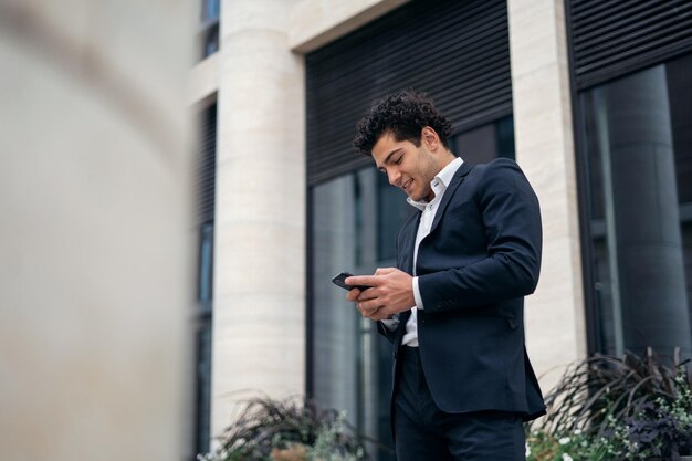 Un gerente de negocios masculino con traje formal usa el teléfono y va a trabajar en la oficina