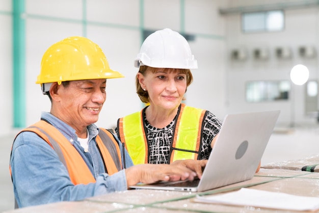 Gerente de negocios de mujer senior con ingeniero de software de programador de almacén que trabaja con computadora de datos de servicio profesional en almacén de almacenamiento y logística de transporte