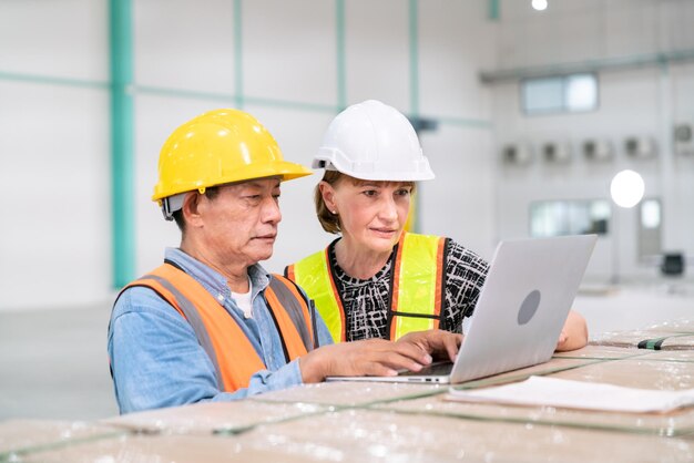 Foto gerente de negocios de mujer senior con ingeniero de software de programador de almacén que trabaja con computadora de datos de servicio profesional en almacén de almacenamiento y logística de transporte