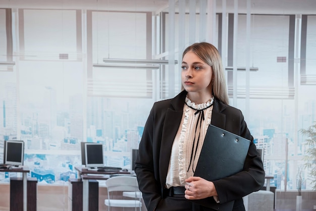 Gerente de oficina caucásica posign en la oficina en el interior y sosteniendo el clipboard