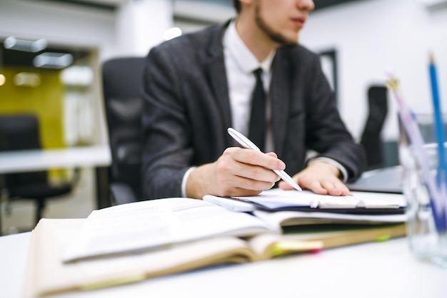 Gerente de oficina joven que trabaja con papeles y computadora en la oficina Revisa y analiza documentos