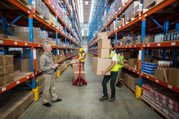 Gerente, olhando para o trabalhador carregando caixas de papelão