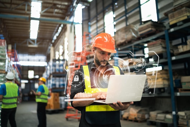 Gerente profesional empleado que usa una computadora portátil para verificar el stock que trabaja en el almacén Trabajador que usa ropa de alta visibilidad y un casco duro y verifica y cuenta los productos o cajas para la entrega