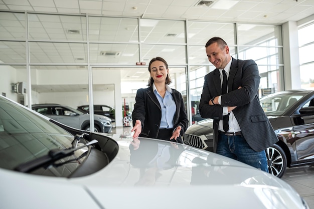 Gerente profissional mostra e leva carro para cliente feminina na concessionária