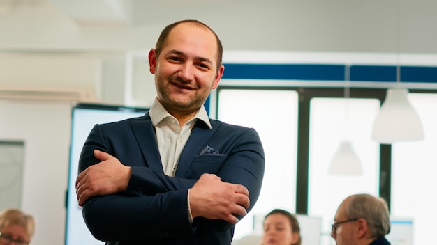 Foto gerente de proyecto joven sonriendo frente a cámara de pie en la sala de intercambio de ideas, preparándose para reunirse con socios. empresario que trabaja en la puesta en marcha profesional de negocios financieros listos para conf