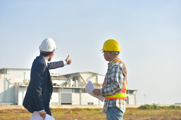 Gerente de proyecto que toma con el ingeniero plan de construcción proyecto de construcción construcción de fábrica