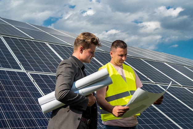 Gerente de proyecto y trabajador discutiendo la instalación de nuevos paneles solares con planos