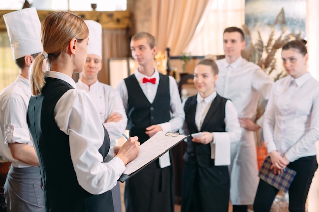 Gerente de restaurante y su personal en cocina. interactuando con el jefe de cocina en la cocina comercial.