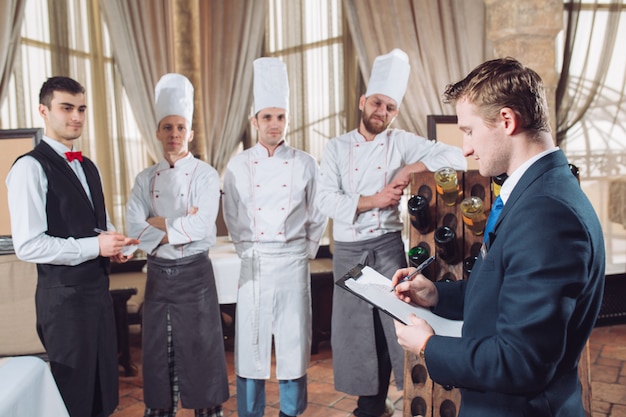 El gerente del restaurante y su personal en la cocina. interactuando con el jefe de cocina en la cocina comercial.