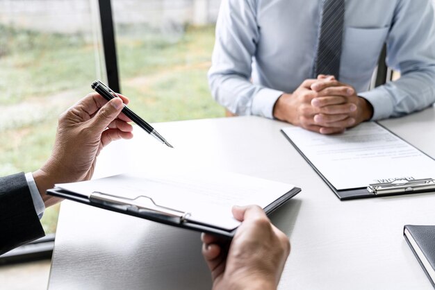 Gerente sénior del comité leyendo un currículum durante una entrevista de trabajo Empleador entrevistando a un joven buscador de trabajo para reclutamiento hablando en la oficina