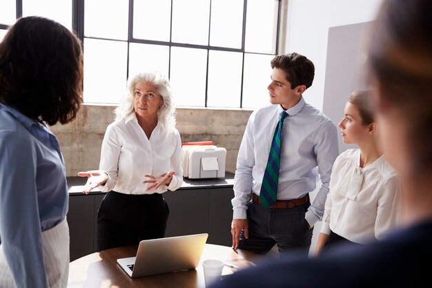 Gerente senior femenina dirigiéndose al equipo en una reunión de negocios