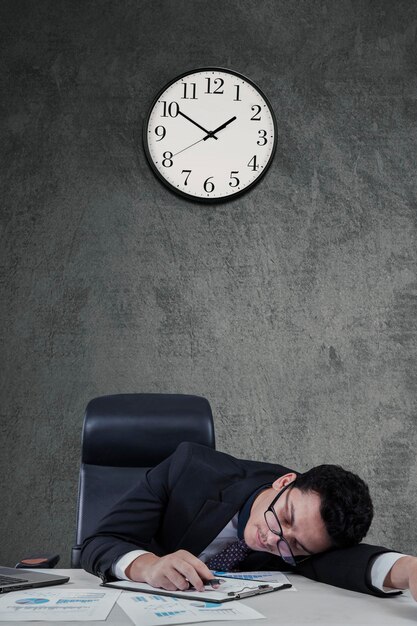 Gerente sobrecargado de trabajo durmiendo en el escritorio