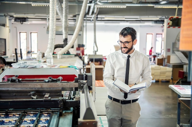 Un gerente sonriente evalúa la calidad de las impresiones en la máquina de impresión