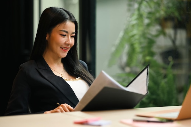 Gerente sonriente revisando el informe financiero o la correspondencia en su lugar de trabajo