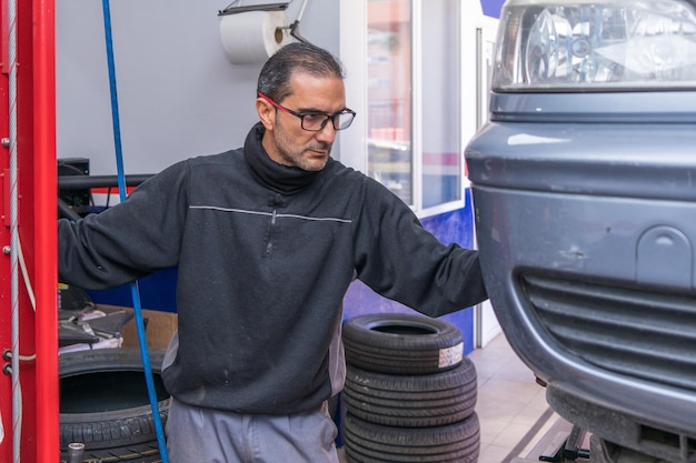 El gerente del taller está levantando un coche para ser revisado