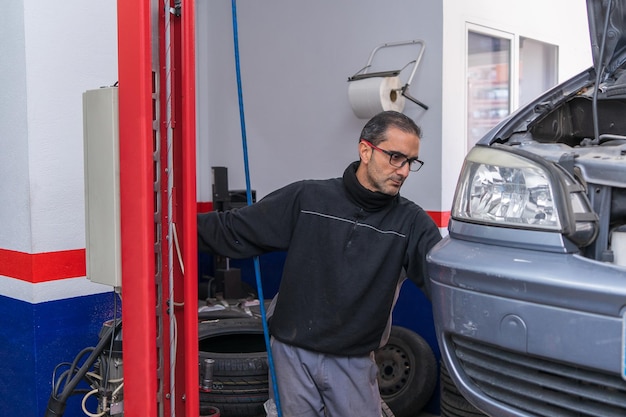 El gerente del taller está levantando un coche para ser revisado