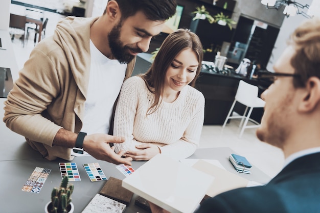 Gerente en traje está mostrando diferentes materiales para los clientes.