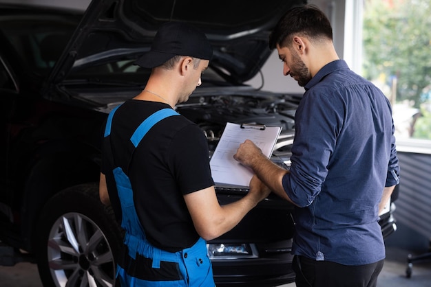 Foto el gerente verifica los datos en una tableta y explica el desglose al empleado del servicio mecánico de automóviles