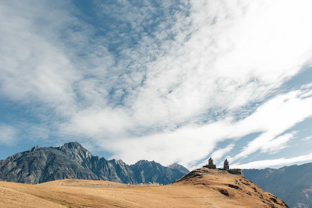 Gergeti Trinity Church bekannt als Tsminda Sameba auf dem Hintergrund eines Bergrückens und Wolken, Stepantsminda, Kazbegi, Georgia.