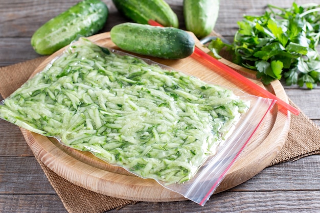 Geriebene Gurke in einer Plastiktüte, die bereit ist, auf einem Holztisch eingefroren zu werden. Tiefkühlkost-Konzept.