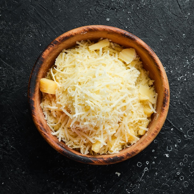 Geriebener parmesankäse in einer schüssel draufsicht des käses auf einem steinhintergrund