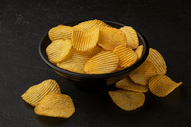 Geriffelte Kartoffelchips auf schwarzem Hintergrund