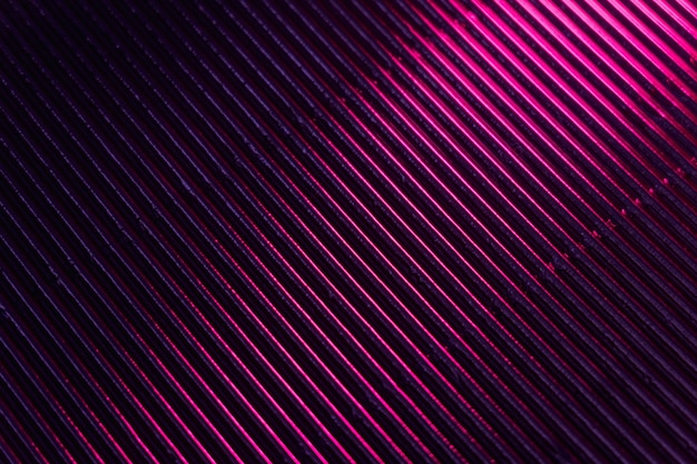 Geriffelte Textur Neonlicht Hintergrund Gerillte Metalloberfläche Fluoreszierende rosa lila Farbverlauf Glühreflexion auf parallelen Linien Muster dunkelschwarze abstrakte Überlagerung