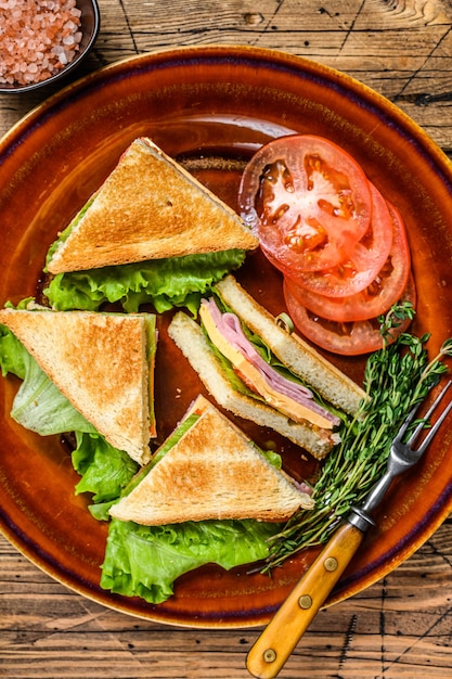 Geröstete Club-Sandwiches mit Schweinefleischschinken, Käse, Tomaten und Salat auf einem Teller