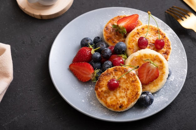 Geröstete Käsekuchen auf einem Teller mit Puderzucker und Beeren Winkelansicht