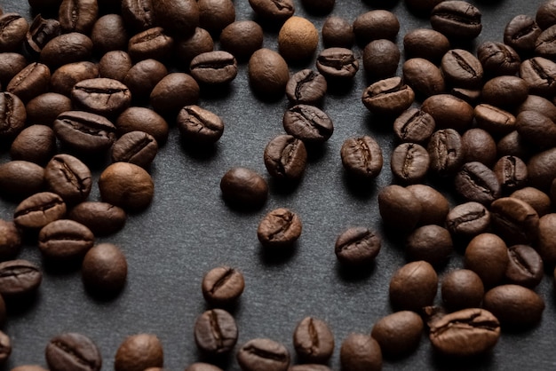 Geröstete Kaffeebohnen auf dunkler Oberfläche verstreut