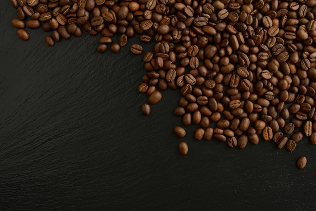 Geröstete Kaffeebohnen auf schwarzem Hintergrund Schöne Kaffeetapete Kaffeebohnen schwarzer Steintisch