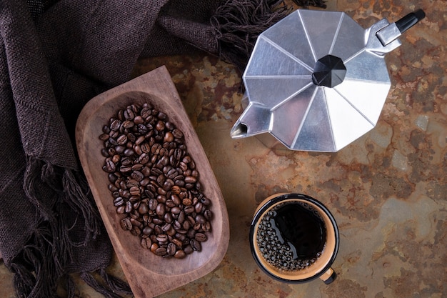 Geröstete Kaffeebohnen, eine Tasse Kaffee und eine traditionelle italienische Kaffeemaschine