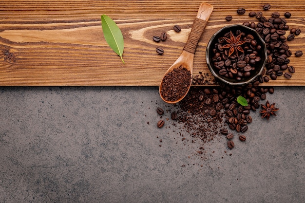 Geröstete Kaffeebohnen mit Kaffeepulver auf dunklem Stein.