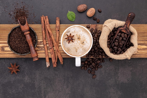 Geröstete Kaffeebohnen mit Kaffeepulver und geschmackvollen Zutaten für leckeres Kaffee-Setup auf dunklem Steinhintergrund