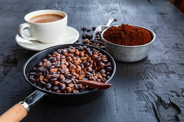 Geröstete Kaffeebohnen mit Kaffeepulver und Kaffeetassen.