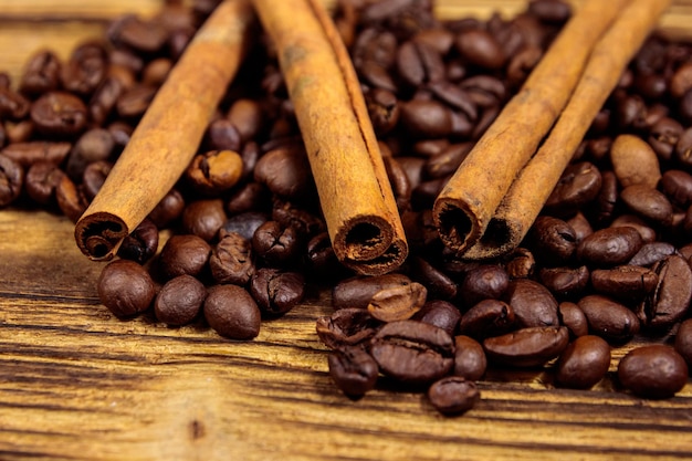 Geröstete Kaffeebohnen und Zimtstangen auf rustikalem Holzhintergrund