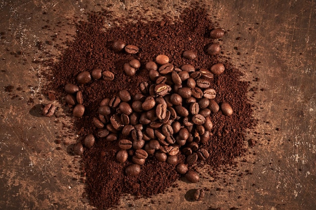 Geröstete Kaffeebohnen unterschiedlicher Art gemahlen und ganz isoliert hautnah auf braunem Grunge-Hintergrund
