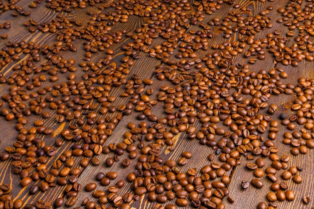 Geröstete Kaffeebohnen verteilt auf Holzbrett-Vollbildhintergrund