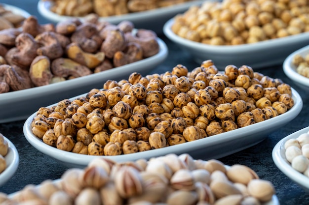 Geröstete Kichererbsen im selektiven Fokus Nüsse auf dem Teller auf dunklem Hintergrund Walnuss-Kichererbsen Weiße Kichererbsen Trockene Maulbeer-Mandel-Cashew-Pistazien Arten von Nüssen auf dem Teller