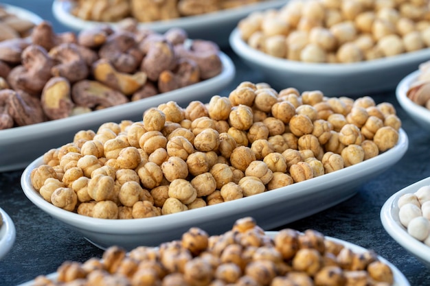 Geröstete Kichererbsen im selektiven Fokus Nüsse auf dem Teller auf dunklem Hintergrund Walnuss-Kichererbsen Weiße Kichererbsen Trockene Maulbeer-Mandel-Cashew-Pistazien Arten von Nüssen auf dem Teller