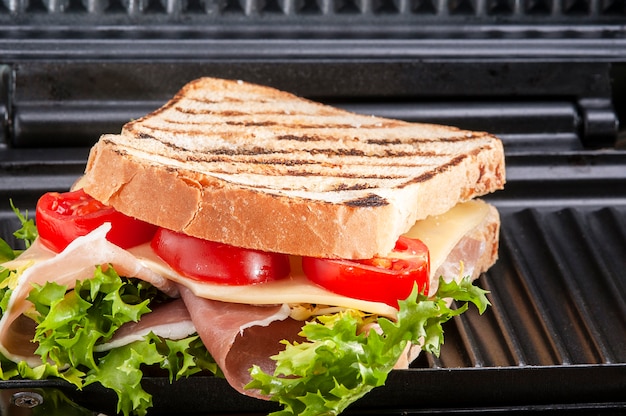 Foto gerösteter sandwich-schinken, käse-tomaten-salat auf einem schwarzen grill