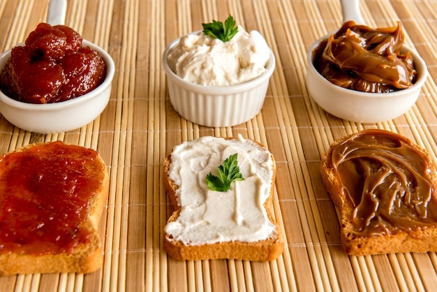 Geröstetes Brot mit Marmelade, Dulce de Leche und Ricottacreme auf einem Frühstückstisch.