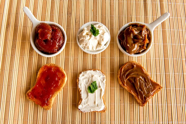 Geröstetes Brot mit Marmelade, Dulce de Leche und Ricottacreme auf einem Frühstückstisch.