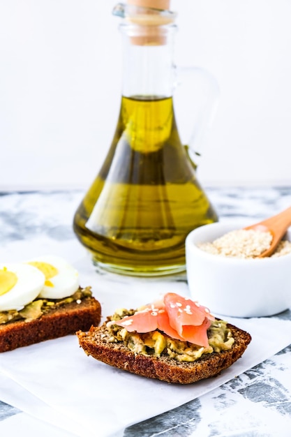 Foto geröstetes brot mit pochierten eiern, avocado und lachs. guacamole-sandwiches. gesundes frühstück. olivenöl. sesamsamen. vegetarische gesunde ernährung.