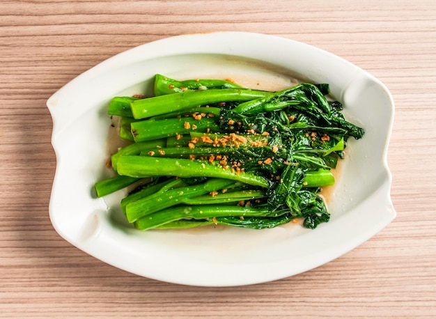 Foto gerührt gebratenes saisonales gemüse chinesisches brokkoli oder kai lan mit gehacktem knoblauch serviert in einem gericht isoliert auf der tischplatte blick auf hongkong essen